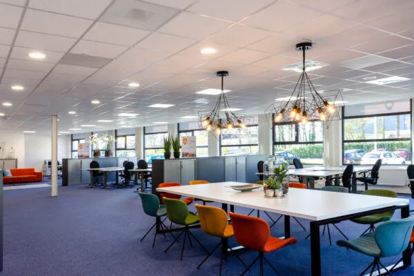 Moderne kantoortuin aan de Niels Bohrweg met kleurrijke stoelen, open werkplekken en industriële hanglampen.